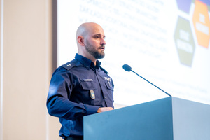 Policjant stoi przy mównicy na auli