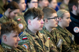 Uczennice i uczniowie z klas mundurowych  siedzą w auli