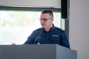 Policjant stoi przy mównicy w auli