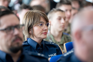 Uczestnicy konferencji i uczniowie siedzą na krzesłach w auli