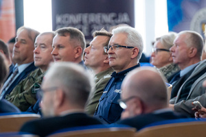 Uczestnicy konferencji, policjanci, żołnierze, uczniowie siedzą na krzesłach w auli