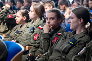 Uczennice i uczniowie z klas mundurowych  siedzą w auli