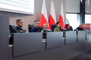 Prelegenci siedzą przy stole konferencyjnym