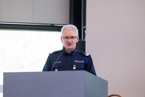 Policjant stoi przy mównicy na auli