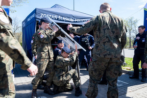 Policyjne stoisko profilaktyczne, uczniowie klas mundurowych, policjanci, uczniowie trzymają tarcze