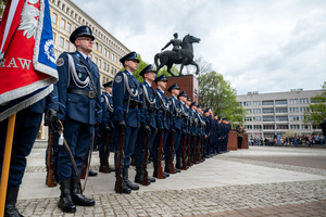 Umundurowani policjanci z Kompanii Honorowej w mundurach galowych stoją przy pomniku na placu
