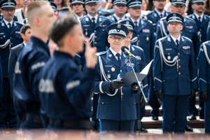 Policjanci w mundurach ćwiczebnych soją  składają ślubowanie, obok przy mikrofonie stoi Generał Policji, za którym stoją policjanci w mundurach galowych