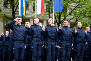 Policjanci w mundurach ćwiczebnych soją  składają ślubowanie, obok stoi policjant w mundurze ćwiczebnym, który oddaje salut