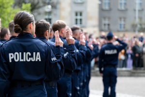 Policjanci w mundurach ćwiczebnych soją  składają ślubowanie, obok stoi policjant w mundurze ćwiczebnym, który oddaje salut