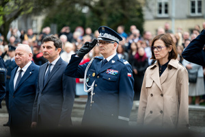 Komendant Wojewódzki Policji wraz z osobami w ubraniach cywilnych stoją w szeregu, Komendant oddaje salut