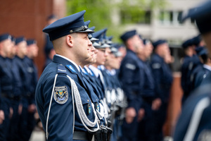 Policjant Kompani Honorowej, w tle policjanci w mundurach ćwiczebnych
