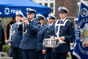 Policjant w mundurze galowym z orkiestry policyjnej gra na trąbce