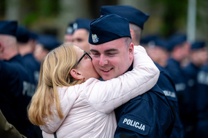 Policjant w mundurze ćwiczebnym stoi przy kobiecie, która go obejmuje