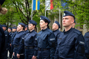 Umundurowane policjantki i policjanci w mundurach ćwiczebnych stoją w szeregach