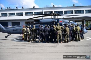 Zdjęcie przedstawia funkcjonariuszy policji, straży granicznej oraz wojska stojących przed śmigłowcem Black Hawk