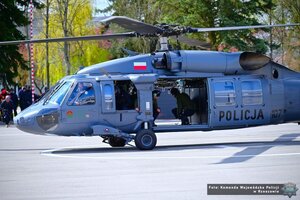 Zdjęcie przedstawia dwóch funkcjonariuszy siedzących na pokładzie śmigłowca