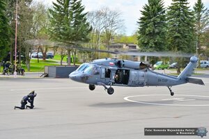 zdjęcie przedstawia unoszący się śmigłowiec nad policjantami