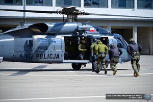Zdjęcie przestawia funkcjonariuszy wbiegających do śmigłowca