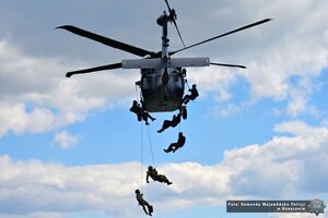 Zdjęcie przedstawia policjantów desantujących się po linie