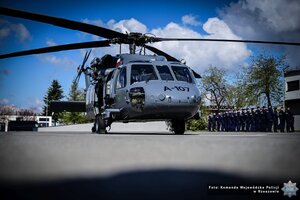 Zdjęcie przedstawia śmigłowiec Black Hawk obok niego stoją funkcjonariusze policji