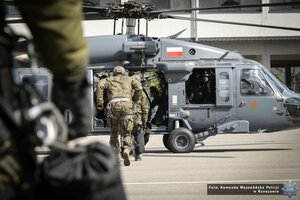 zdjęcie przedstawia funkcjonariuszy wbiegających do śmigłowca