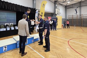 Zdjęcie przedstawia chłopca stojącego na podium oraz policjantów wręczających mu nagrodę