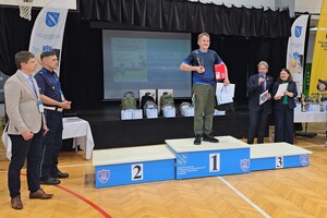 Zdjęcie przedstawia chłopca stojącego na podium z pucharem oraz nagrodami