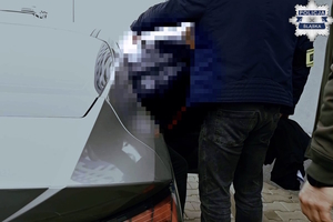 Zdjęcie przedstawia moment umieszczenia osoby zatrzymanej w pojeździe.