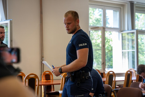 policjant idzie z kartką w rękach