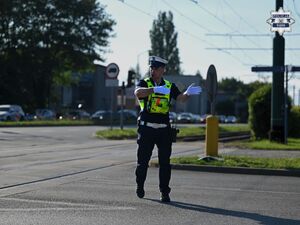 Na zdjęciu widoczny jest policjant ruchu drogowego podczas kierowania ruchem.