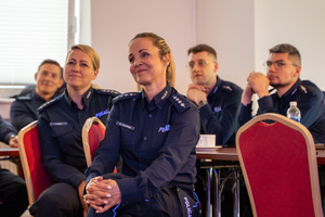 Zdjęcie z przybliżenia na siedzącą grupę policjantów.