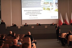 Zdjęcie przedstawia zasiadających na widowni szkolących się policjantów. W ich tle widoczna jest prowadząca szkolenie policjantka