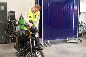 Na zdjęciu widoczny jest uczestnik turnieju, którzy spogląda i trzyma motocykl.