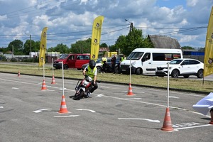 Zdjęcie przedstawia osobę poruszającą się na skuterze po stworzonym torze przeszkód.