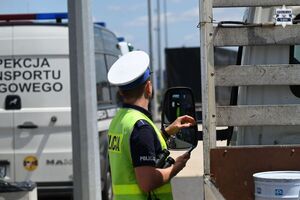 Zdjęcie przedstawia umundurowanego policjanta w trakcie czynności służbowych