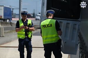 Na zdjęciu widocznych jest dwóch policjantów w trakcie kontroli pojazdu ciężarowego