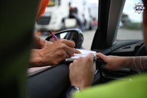 Na zdjęciu widoczny jest z bliska moment podpisywania mandatu karnego wystawionego przez policjanta