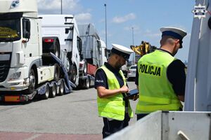 Zdjęcie przedstawia dwóch umundurowanych policjantów w trakcie wykonywania czynności służbowych