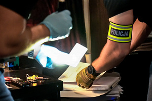 Na zdjęciu widoczne są częściowo sylwetki policjantów w trakcie przeglądania dokumentacji
