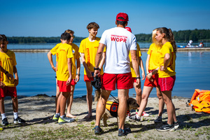 Zdjęcie przedstawia ratowników wodnych - ochotników stojących na plaży