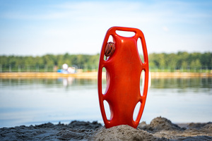 Na zdjęciu widoczna jest deska ratunkowa wbita w piasek na plaży