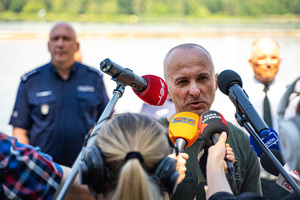 Na zdjęciu widoczny jest gość imprezy w trakcie udzielania informacji do prasy. W tle widoczny jest Zastępca Komendanta Wojewódzkiego Policji w Katowicach