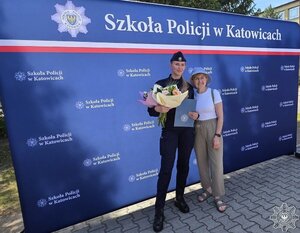 Na zdjęciu policjantka wraz z osobą bliską z rodziny, na ściance policyjnej.