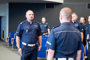 Na zdjęciu widocznych jest grupa policjantów stojących na sali.