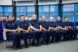 Zdjęcie przedstawia siedzących policjantów na sali.