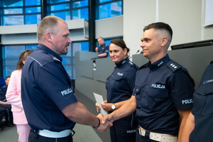 Na zdjęciu widoczni są policjanci, z których dwóch podaje sobie dłoń.