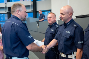 Na zdjęciu widoczni są gratulujący sobie policjanci.