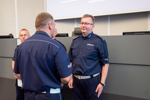Na zdjęciu widać policjantów, którzy stoją naprzeciwko siebie