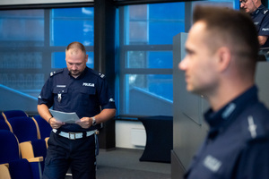 Na zdjęciu widać policjanta niosącego list okolicznościowy w ręce.