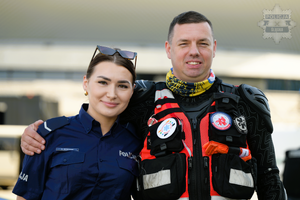 Umundurowana  policjantka z ratownikiem medycznym pozujący do zdjęcia.